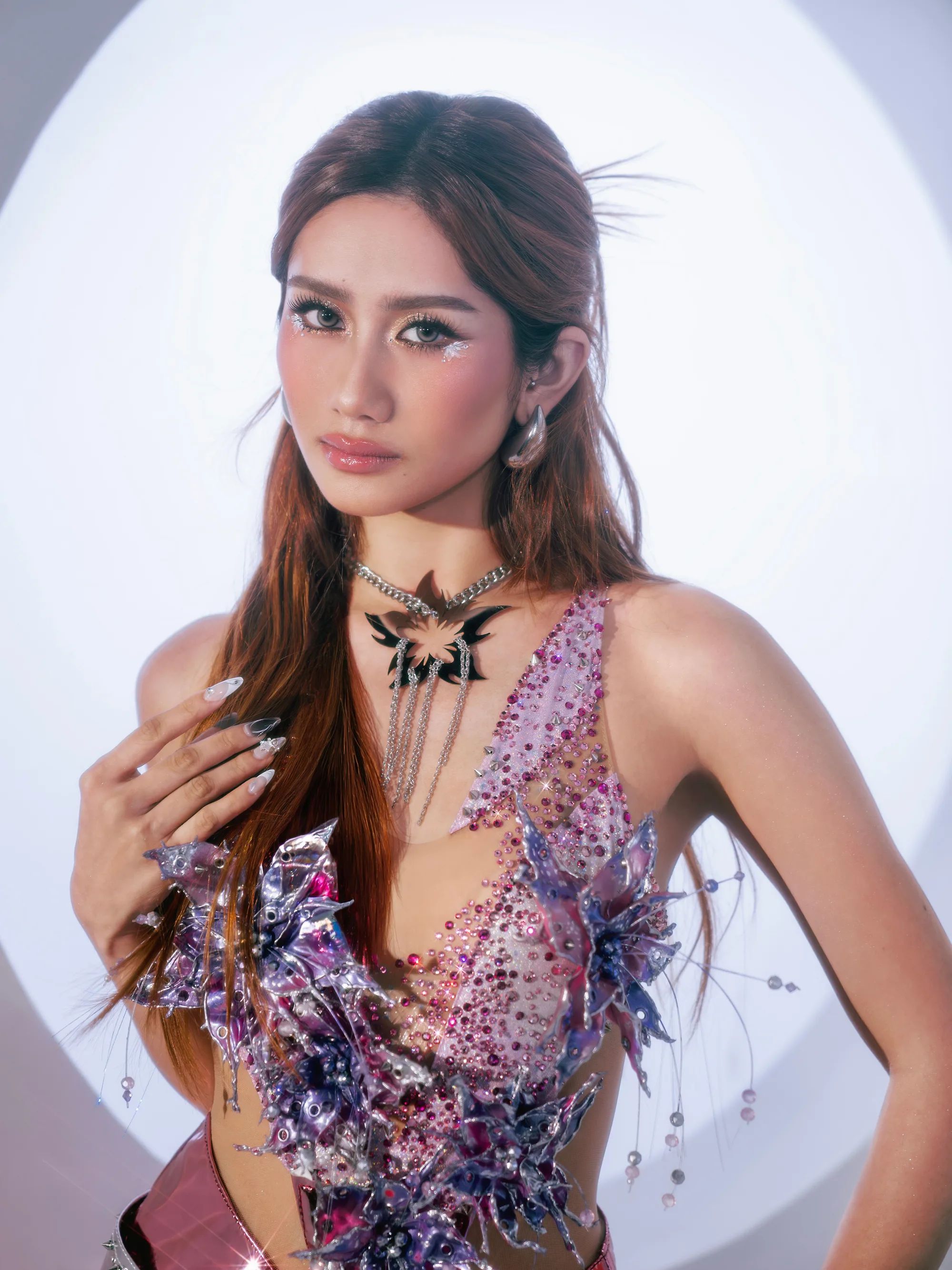 A BINI member with a butterfly choker, in a jeweled lilac top